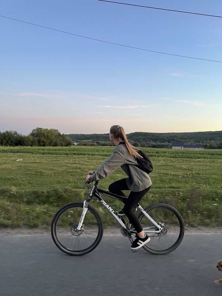 Rider on a mountain-style bicycle beside open fields at dusk