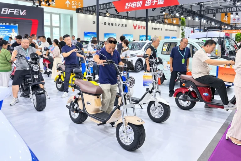 Visitors viewing and trying seated electric scooters at an exhibition.