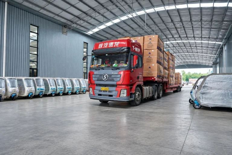 A loaded truck alongside prepared vehicles in the workshop.
