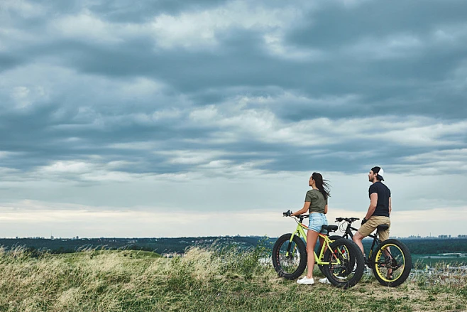 Two people standing with fat-tire bicycles in an open landscape