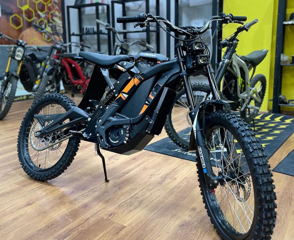 Electric dirt bikes on display with off-road tires, front suspension and frame components visible